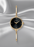 Gold watch with black face on a gray fabric background