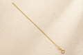 9ct Yellow Gold 1.1mm Classic Curb Chain on champagne textured background