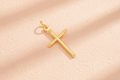 9ct Yellow Gold Round Tube Cross Pendant on peach textured background