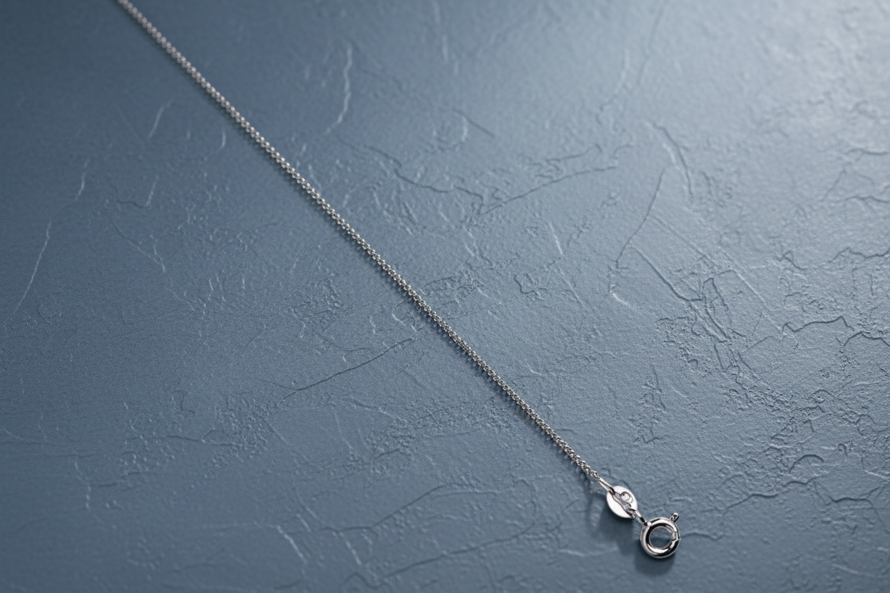 9ct White Gold 1.1mm Classic Curb Chain on slate blue textured background