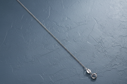 9ct White Gold 1.1mm Classic Curb Chain on slate blue textured background