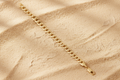 9ct Yellow Gold 7.4mm Flat Curb Chain on warm sand textured background
