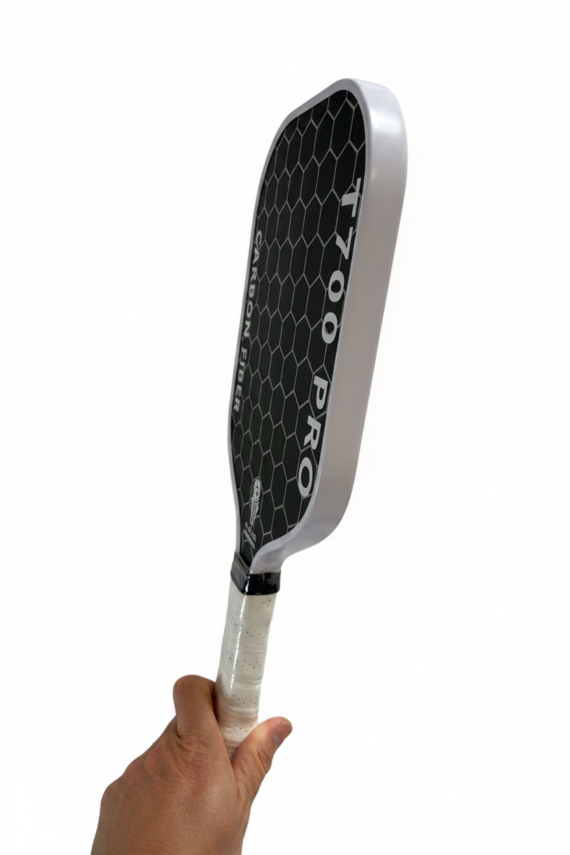Pickleball paddle with 'T700 Pro' branding held against a textured white wall.