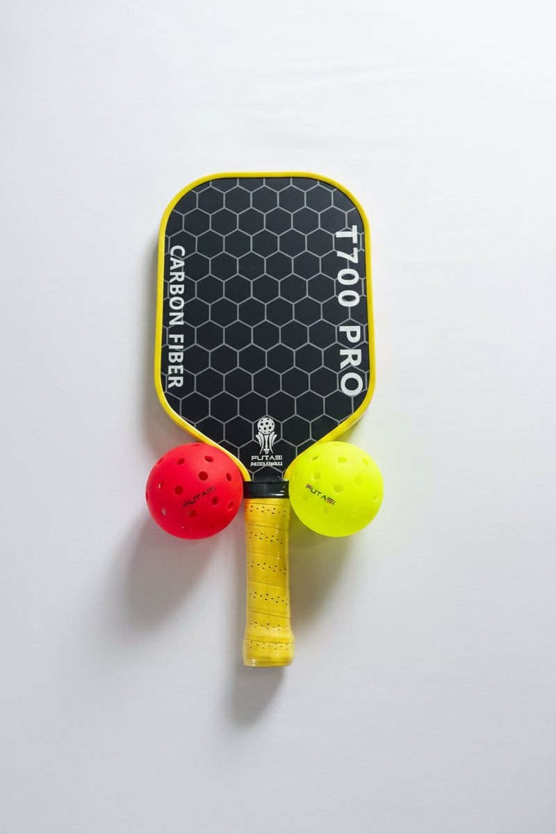 Pickleball paddle with 'T700 Pro' branding and two balls on a light gray surface