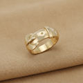 9ct Yellow Gold Buckle Ring on warm tan textured background