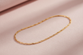 9ct Yellow Gold Figaro Anklet on soft pink textured background