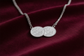 Silver double half sovereign coin necklet on rich burgundy velvet background