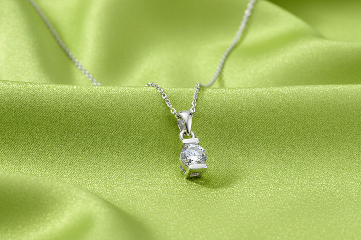 Silver CZ pendant on chain on lime satin textured background