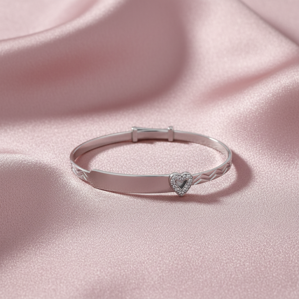 Silver Babies' Round CZ Heart ID Bangle flat lay on dusty rose silk