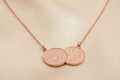 Rose gold plated double sovereign coin necklet on warm ivory satin background