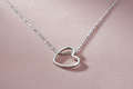Silver rhodium plated open heart pendant on dusty rose background