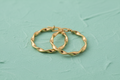 9ct Yellow Gold 26mm Twisted Hoop Earrings on mint green textured background