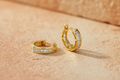 9ct Yellow Gold 12mm Princess Cut CZ Huggie Earrings on warm amber textured background