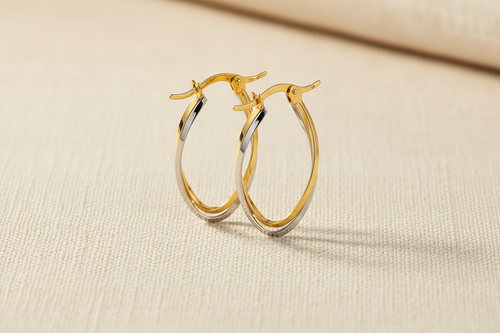 9ct Yellow & White Gold Two Colour Twist Oval Hoop Earrings on cream linen textured background