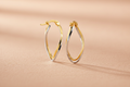9ct Yellow & White Gold Twist Oval Hoop Earrings on peach textured background